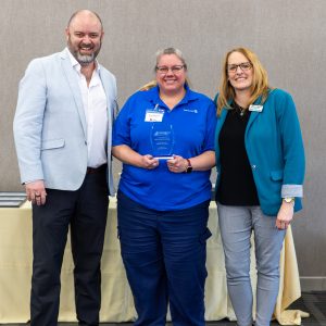 A woman receiving an award from Clarington Board of Trade at a formal event with business leaders.