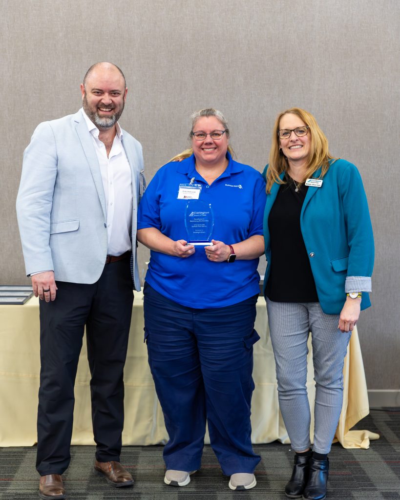 A woman receiving an award at Clarington Board of Trade event with two colleagues.