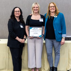 A woman receiving an award for 75 years of service in Clarington at a business event.