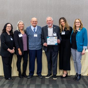 People holding an award certificate at a Clarington business event.