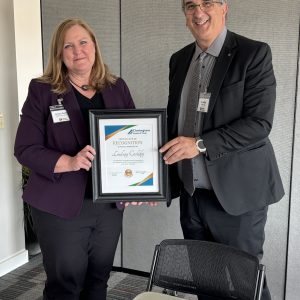 Alt text: Woman receiving recognition award from man at Clarington Board of Trade meeting.