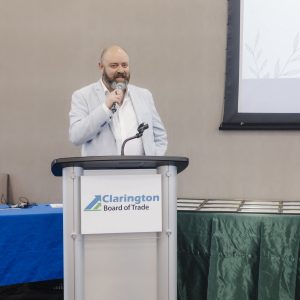 Man speaking at Clarington Board of Trade event with presentation screen.