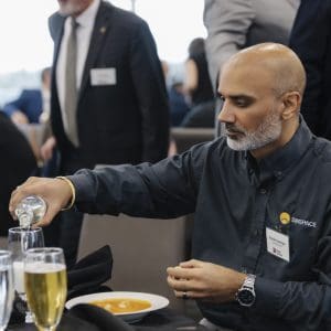 Business professional pouring drink at Clarington Board of Trade event.