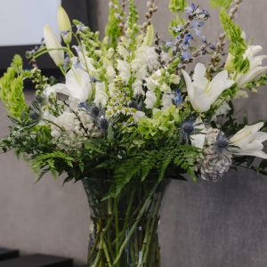 Floral arrangement for Clarington Board of Trade event, featuring white lilies, blue thistles, and g.