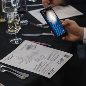 Business networking event with people using smartphones and documents.